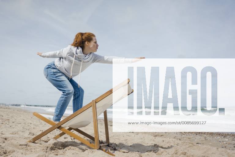 Woman standing on deck chair, pretending to surf model released Symbolfoto KNSF04303