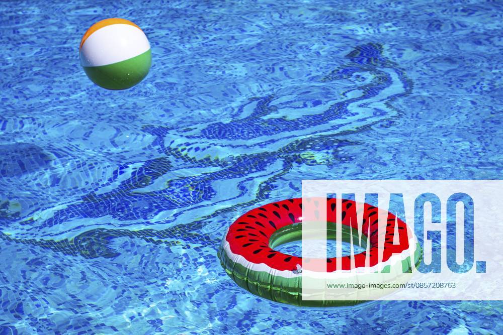 Bunter Wasserball und Wassermelonenkreis, schwimmend im Poolwasser, an einem sonnigen Sommertag, keine Menschen Colorful beach ball and watermelon circle, floating in the pool water, on a sunny summer day, no people