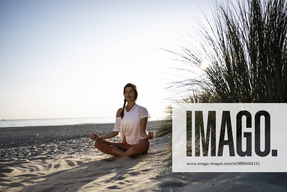 Woman practicing yoga and meditating on a sandy summer beach model released, Symbolfoto, UUF36836