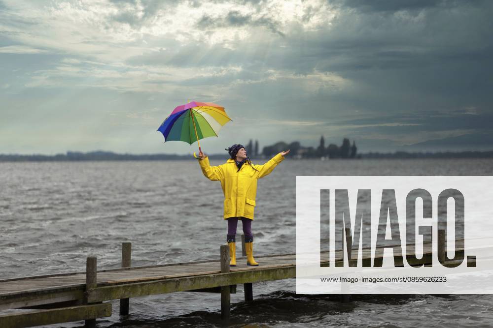 Junge Frau hält bei Wind und Sturm den Schirm fest in der Hand, Steinhude, Niedersachsen, Deutschland Young woman holding her umbrella firmly in her hand during wind and storm, Steinhude, Lower Saxony, Germany