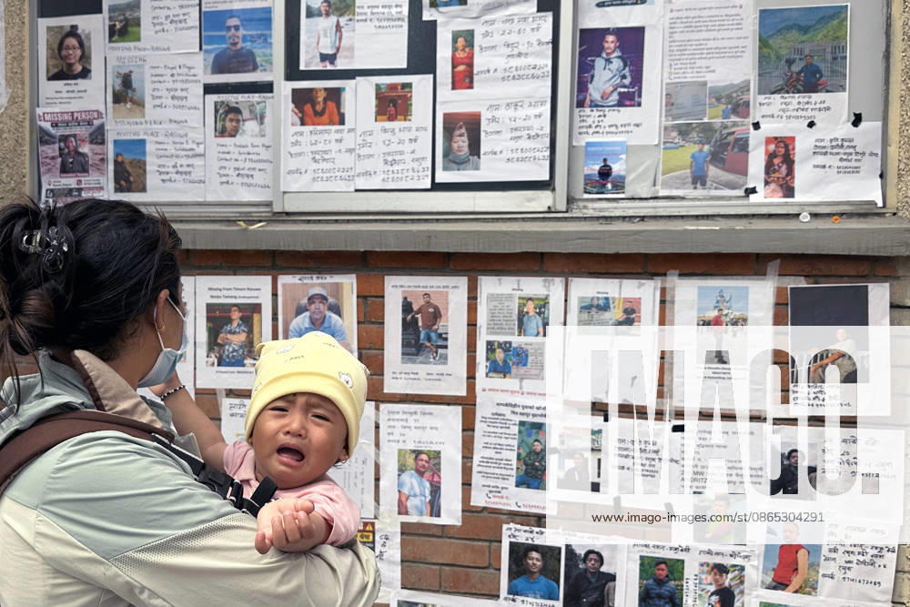 A woman along with her baby searches for missing family members as photographs of missing people are displayed outside the hospital, four days after devastating flash floods struck areas near the Nepal-China border at Tribhuvan University Teaching Hospital in Maharajgunj, Kathmandu,Nepal on August 30, 2026. According to authorities, 734 people had died and 2,498 remained missing as morning of Aug. 30, 2026, following devastating flash floods that struck areas near the Nepal-China border on Aug. 26. Kathmandu Nepal - ZUMAs233 20260830_zap_s233_010