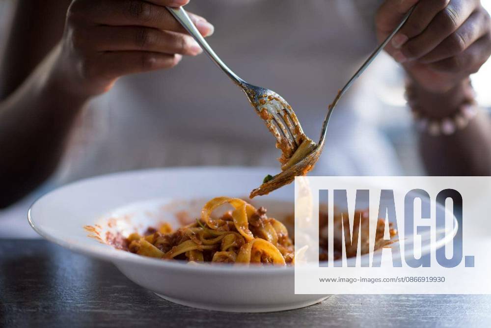 Young beautiful African American woman enjoys while eating delicious pasta model released Symbolfoto