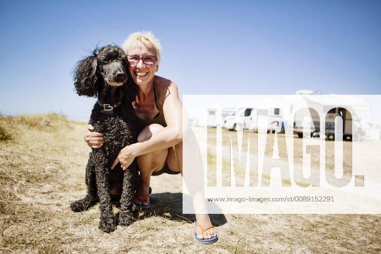 Woman embraces her dog king poodle at a campsite Portbail Normandie France Europe