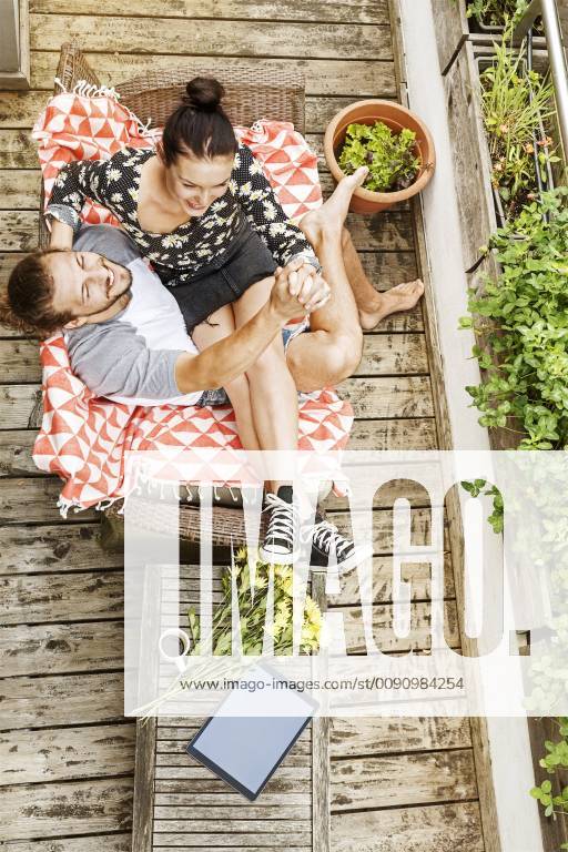 Young couple sitting on their balcony in summer, holding hands model released Symbolfoto property released PESF01185