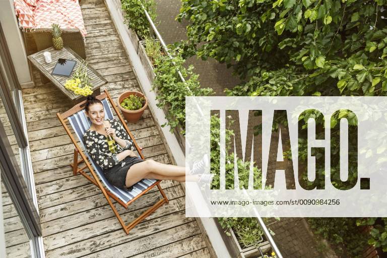 Young woman sitting in deck chair, relaxing on her balcony model released Symbolfoto property released PESF01187