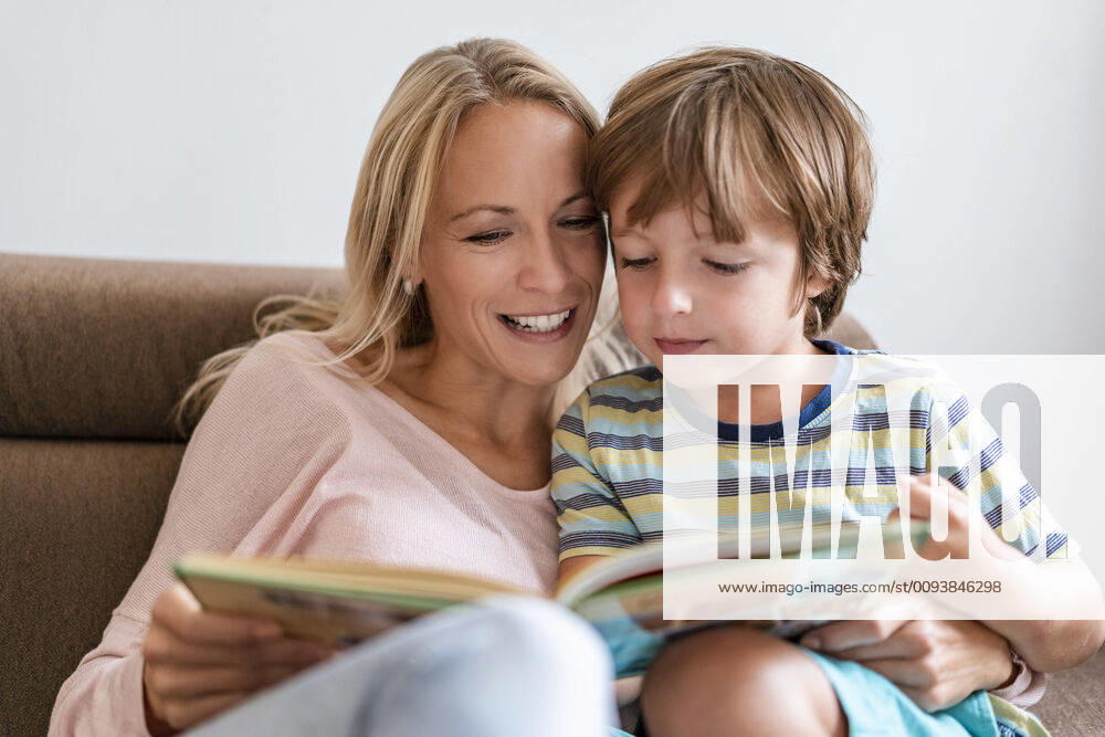 Mother and son reading a book together on couch at home model released Symbolfoto property released DIGF08133
