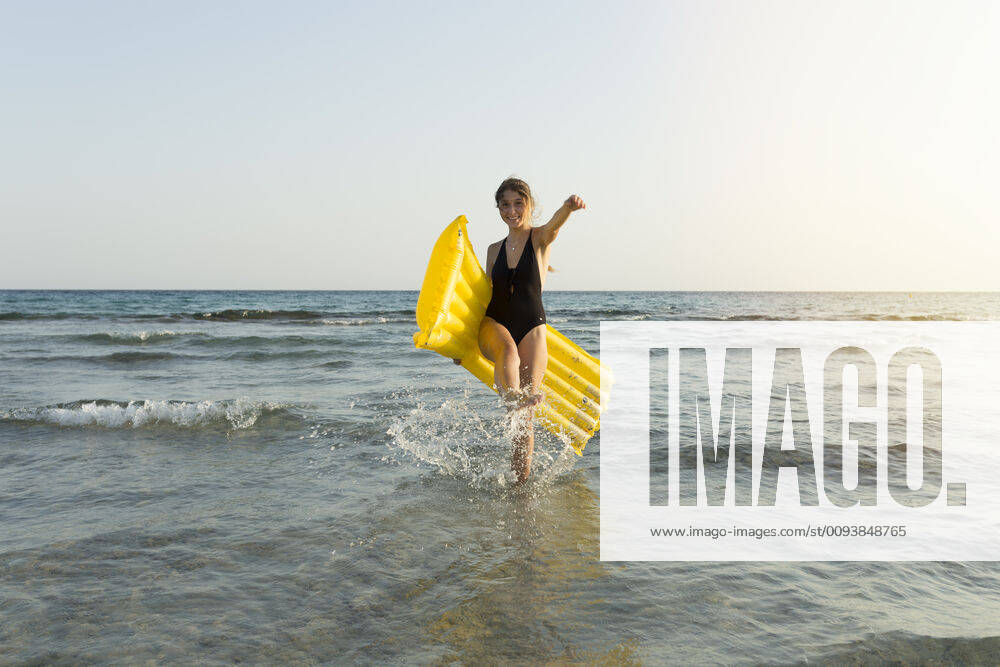 Young woman with yellow airbed at the beach model released Symbolfoto JPTF00268