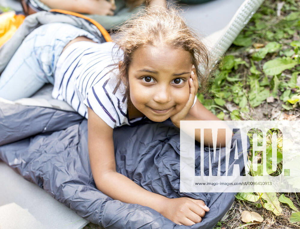 Little girl lying on sleeping bag, looking at camera model released Symbolfoto WESTF24487