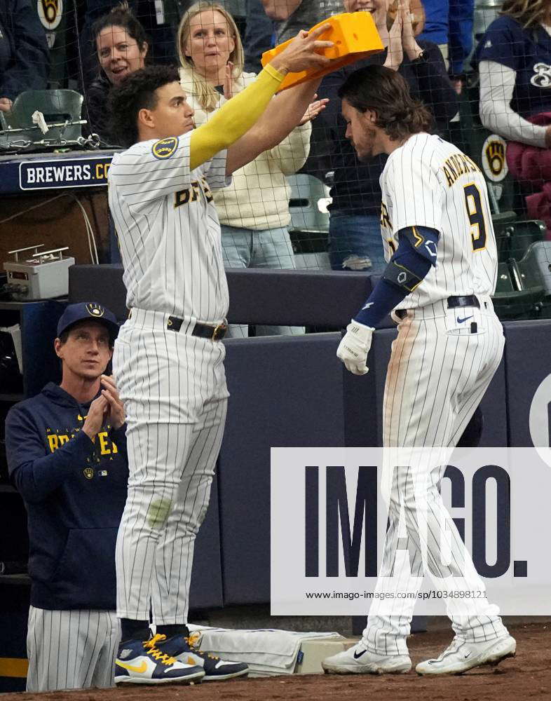 Milwaukee Brewers' Willy Adames, left, places a cheesehead on