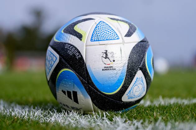 Ein Ball der Marke adidas Oceaunz Pro Competition Ball liegt auf dem Rasen und zeigt das Logo der