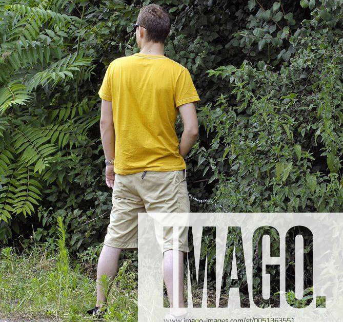 Junger Mann pinkelt in ein Gebüsch während der Loveparade 2006 in