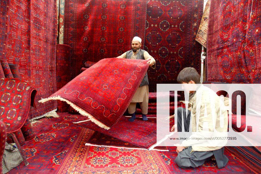 Teppichhändler zeigt einem Kunden einen Teppich in einem Teppichgeschäft in Kabul