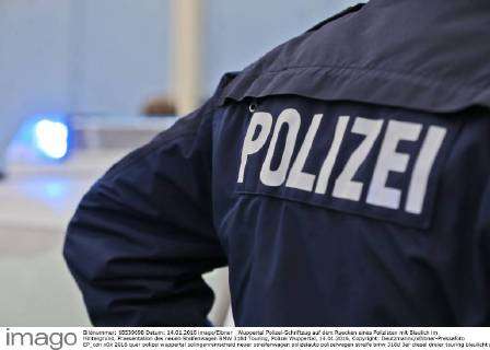 Wuppertal Polizei-Schriftzug auf dem Ruecken eines Polizisten mit Blaulich  im Hintergrund