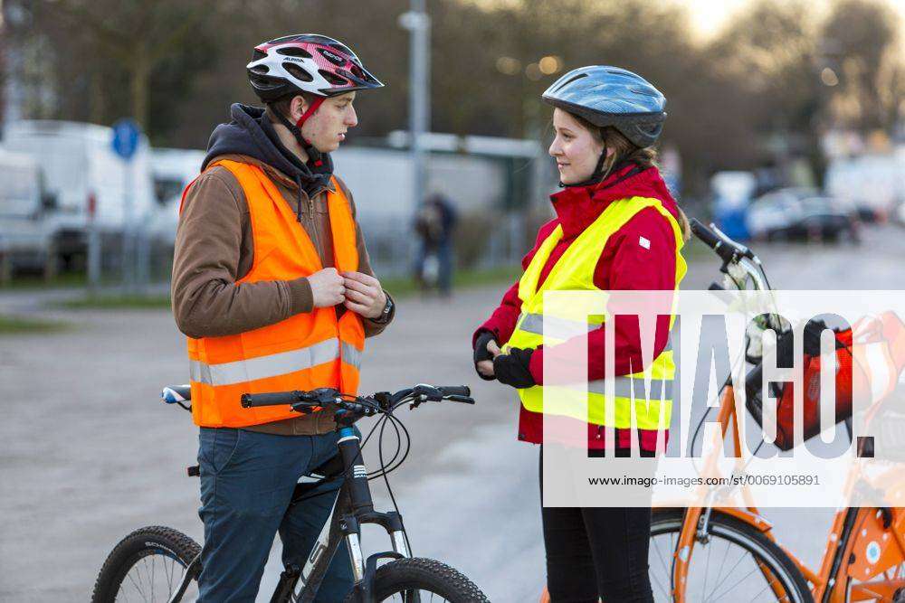 Radfahrer ziehen sich Sicherheitsbekleidung, Helm, Warnweste, vor