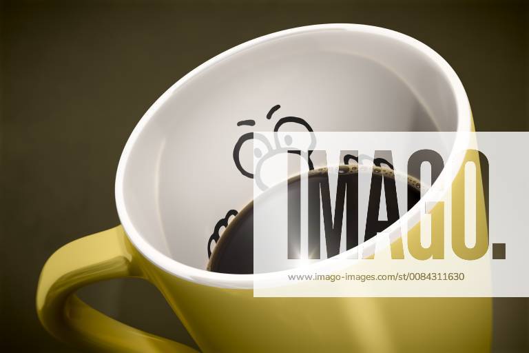 Eine gelbe Tasse Kaffee vor braunem Hintergrund, mit einem Gesicht mit grosser Nase auf der