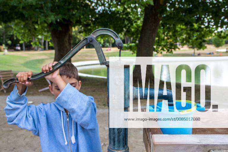 Kind bedient Handpumpe im Freien Schwengelpumpe spendet Wasser