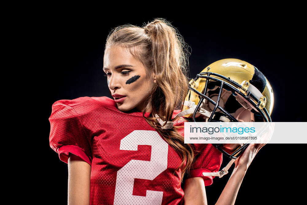 Female football player posing with helmet Attractive female american  football player in uniform