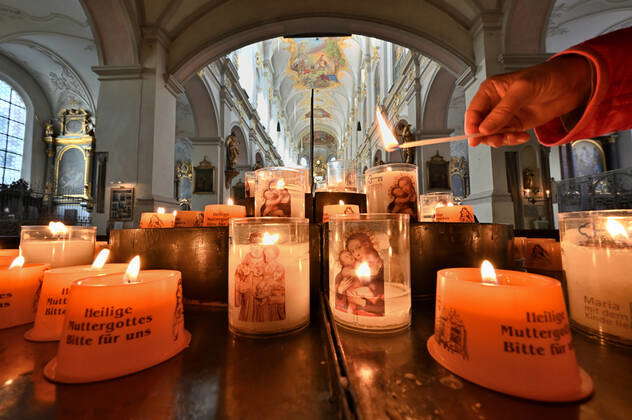 Leuchtende Kerzen. Eine Kerze wird in der Stadtpfarrkirche St.Peter in München entzündet, jedes