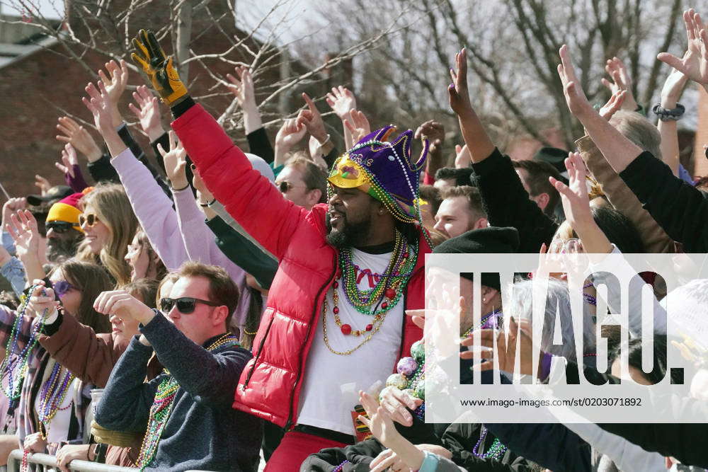 Parade goers yell for beads as a float passes during the St. Louis