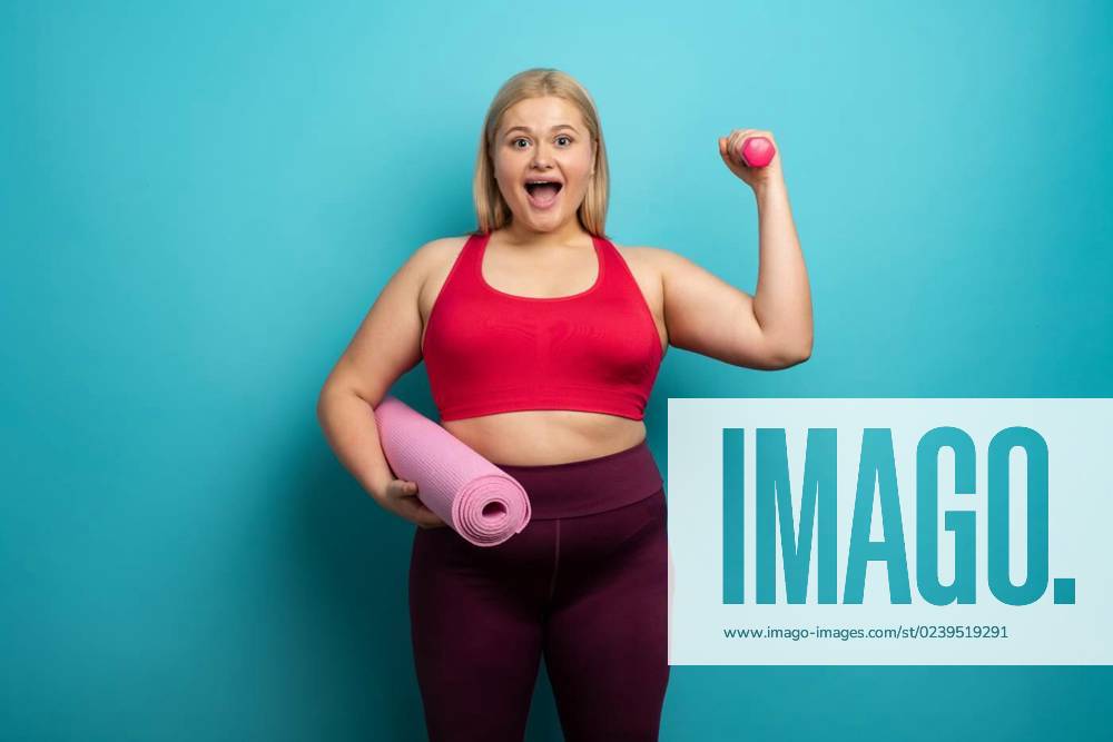 Fat girl does gym at home. satisfied expression. Cyan background, Fat girl  does gym at home