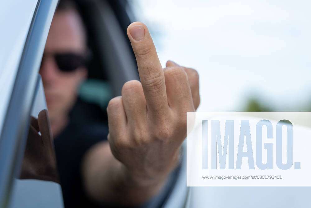 wütender Autofahrer zeigt einen Mittelfinger als Beleidigung im  Straßenverkehr. Fahrer zeigt