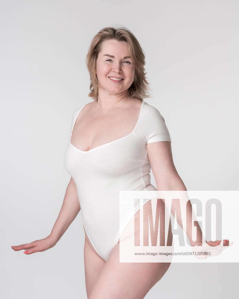 Portrait of happy plump mature adult woman in white body suit posing in  studio on white