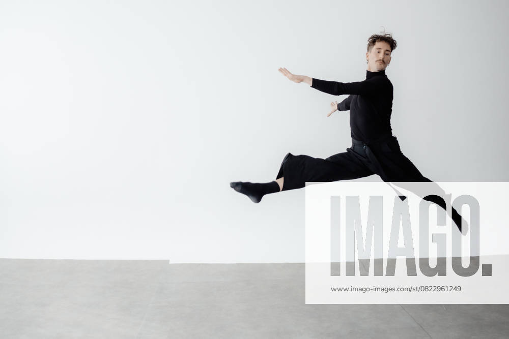 A dancer in black clothing performing a dynamic leap indoors in Berlin ...