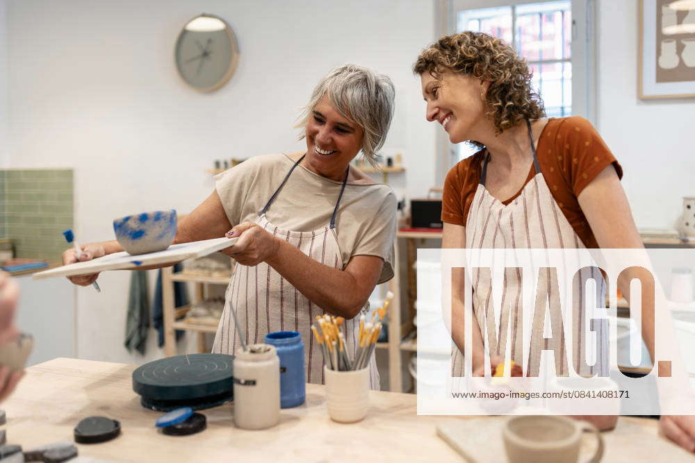 Friends creating ceramic art in a pottery class workshop smiling ...