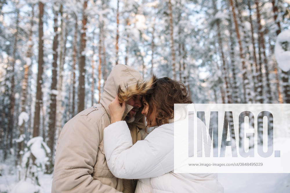Couple embracing outdoors in warm clothing in snowy winter forest model ...